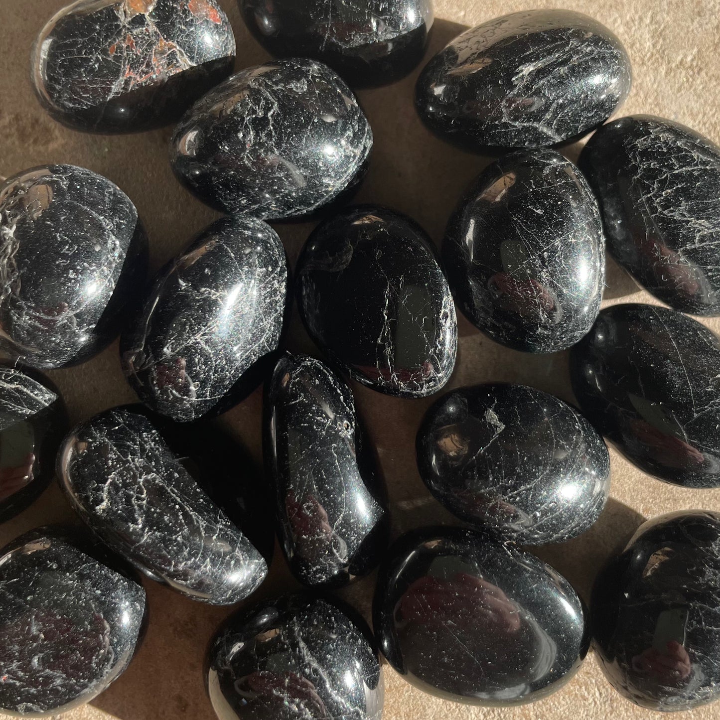 A group of Black Tourmaline Tumbles on stone background.