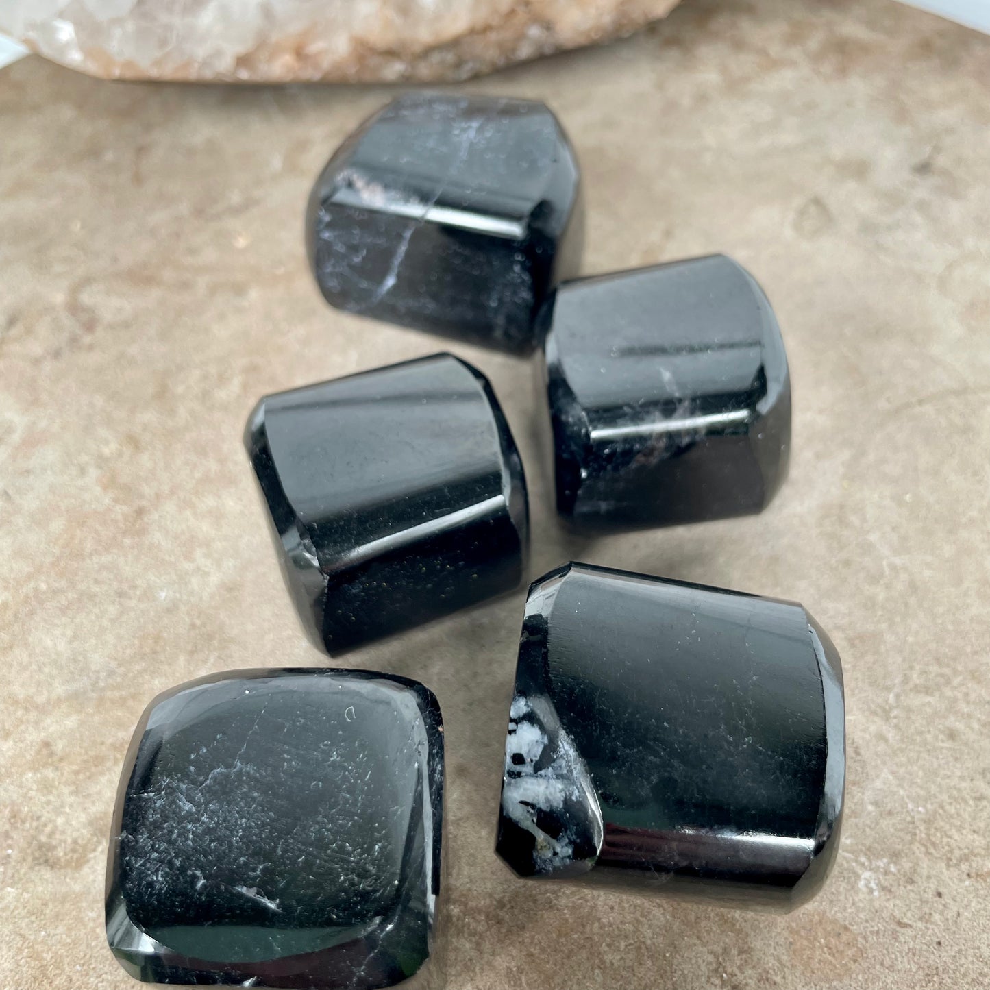 Five Black Tourmaline Free Form Cubes sitting on a stone bench.