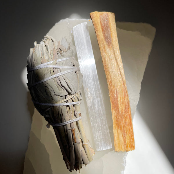 White Sage, Selenite and Palo Santo Stick lying on a crystal.