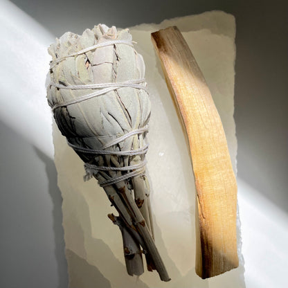 White Sage and Palo Santo Stick lying on a piece of crystal.