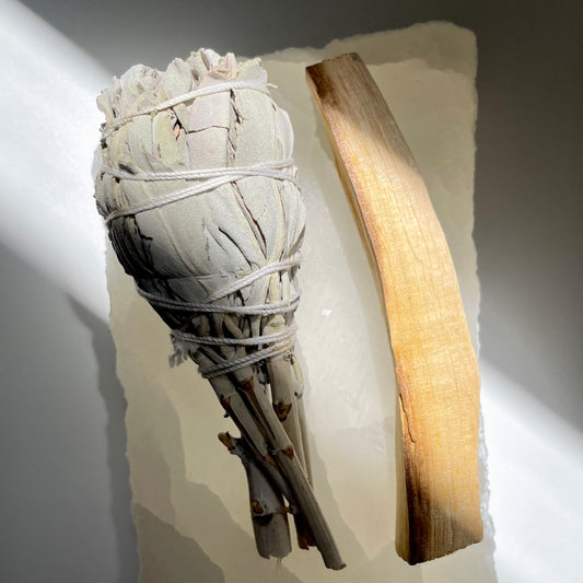 White Sage and Palo Santo Stick lying on a piece of crystal.