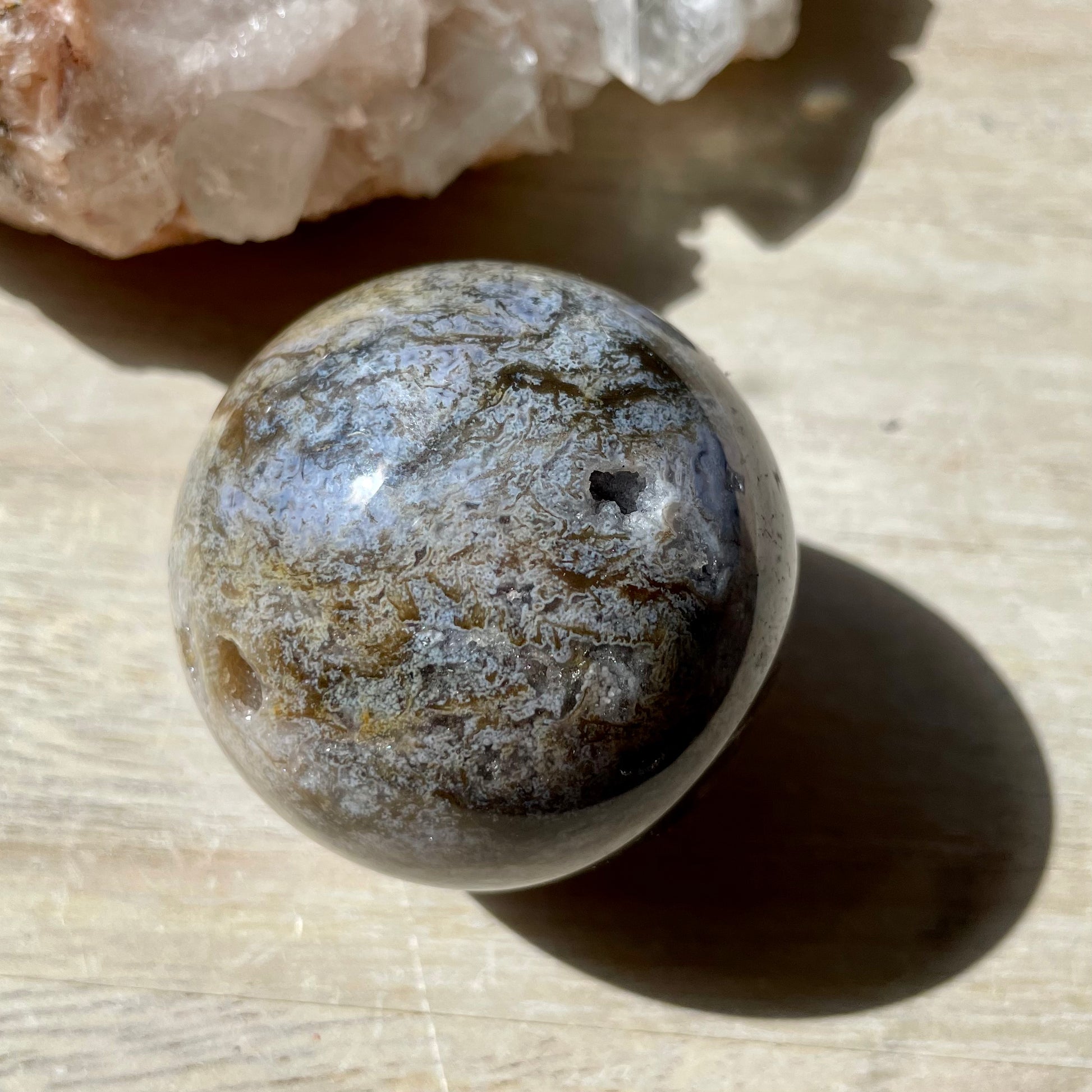 Moss Agate Purple Sphere on wooden background