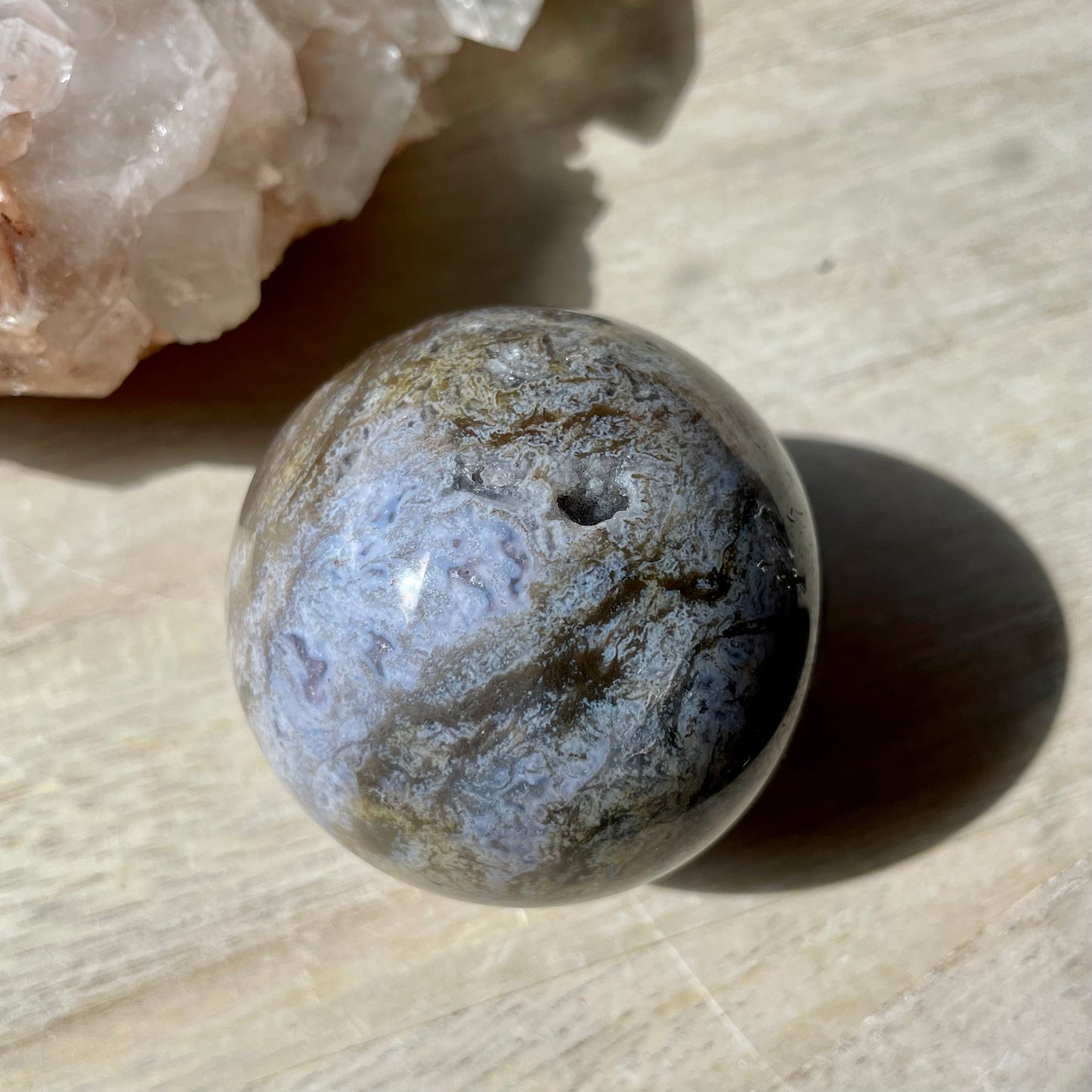 Moss Agate Purple Sphere on wooden background